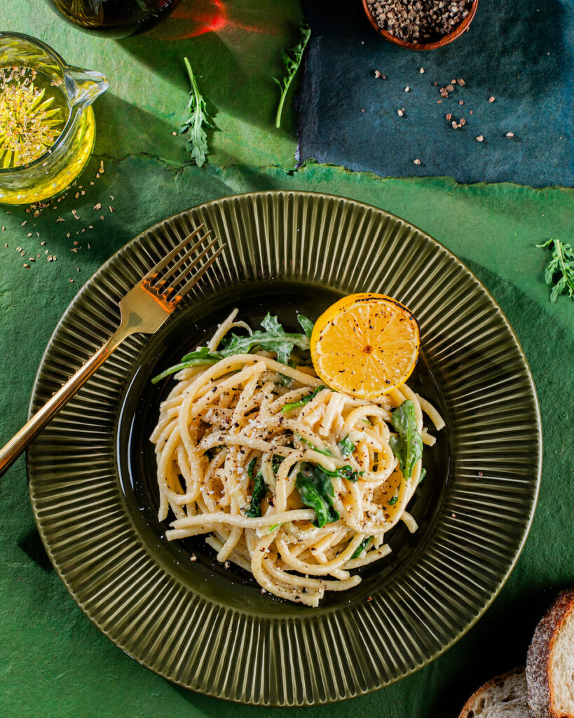 A plate of cacio e pepe on a green background