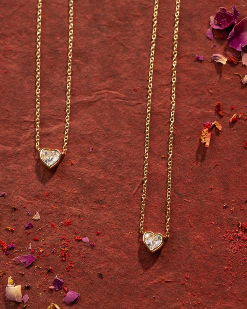 Two gold heart chains lay on an orange background.