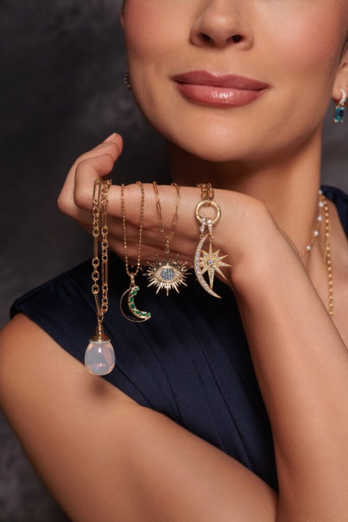 A woman holds various chain necklaces on her hand.