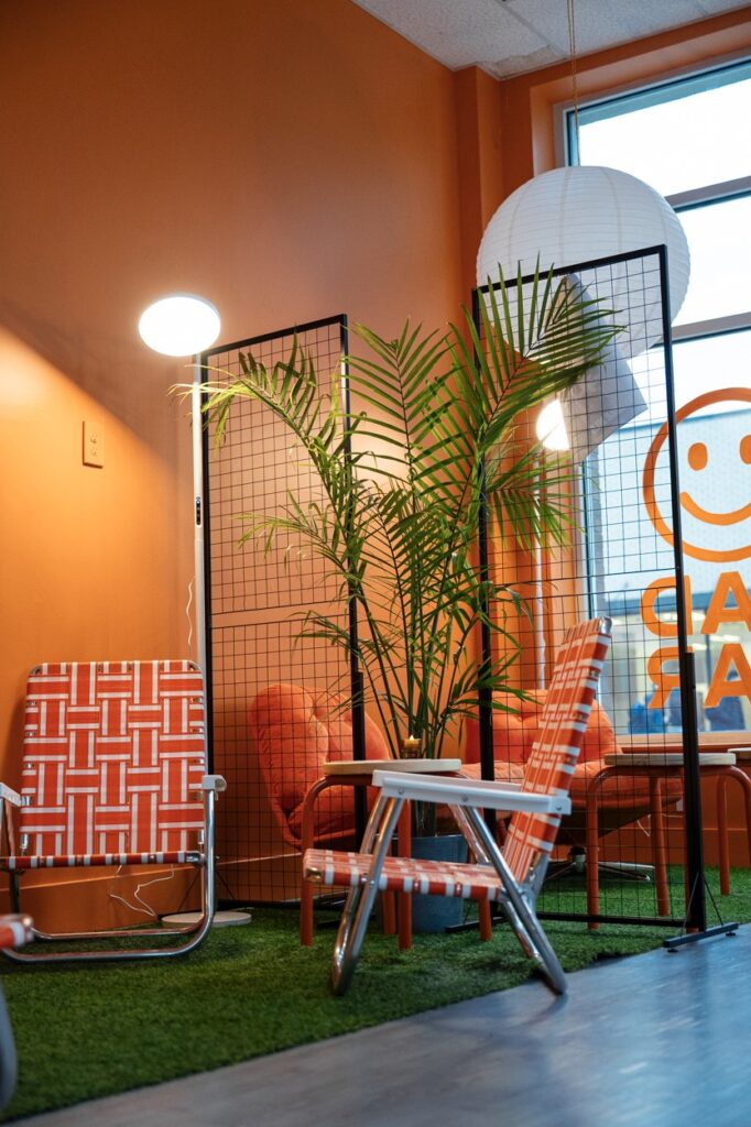 Two lawn chairs sit amongst orange walls and plants.