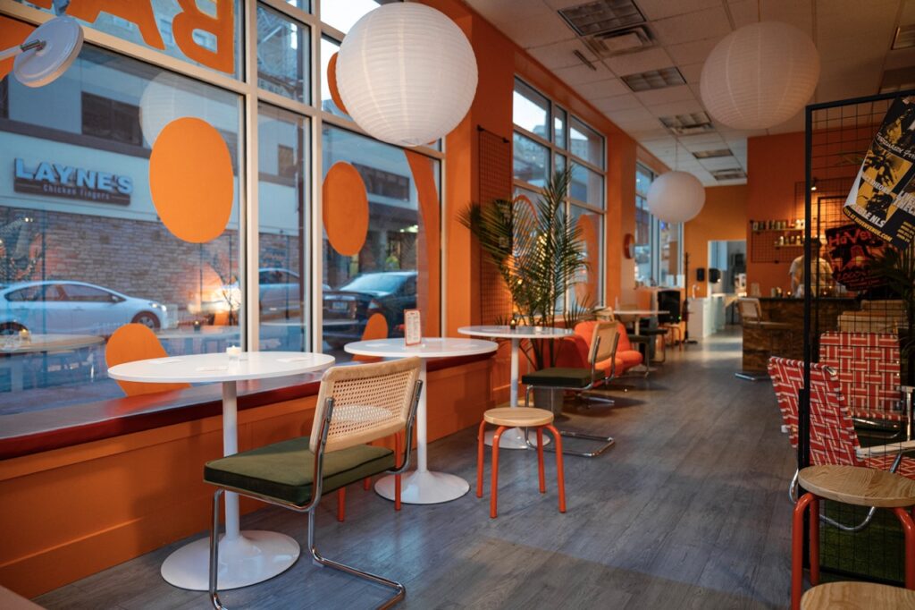 Tables sit against windows while walls sit in bright orange.