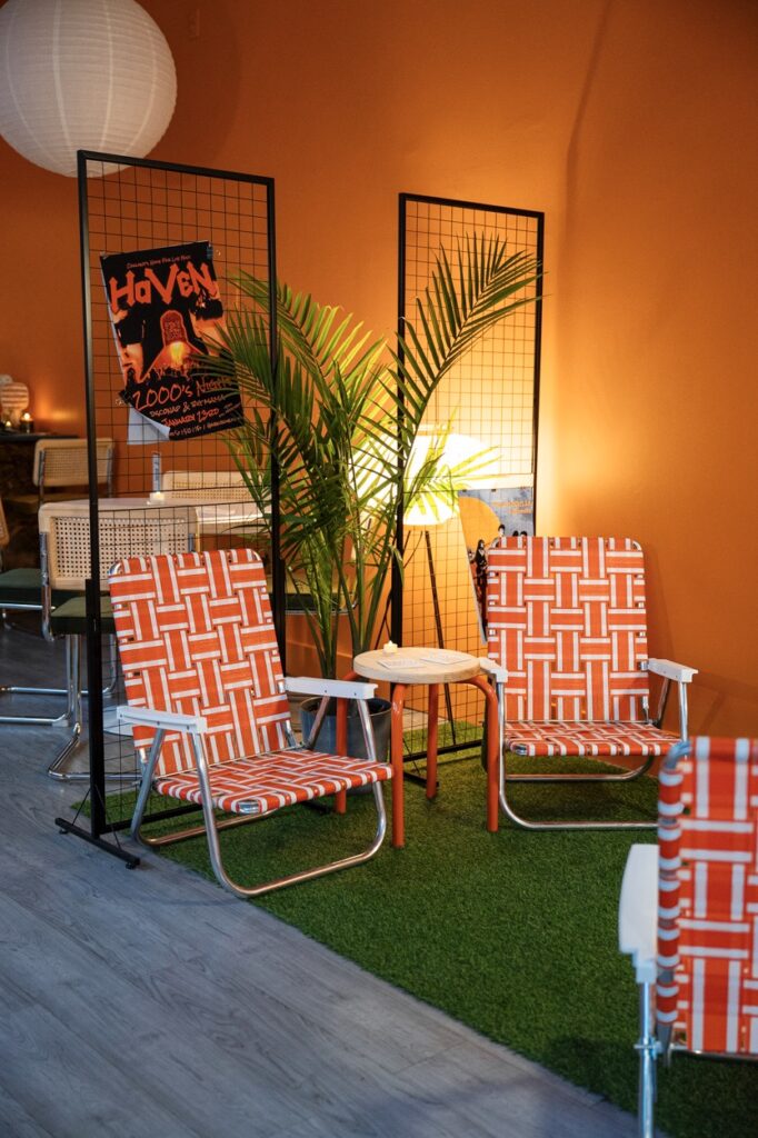 Two orange lawn chairs sit on a fake green patch.