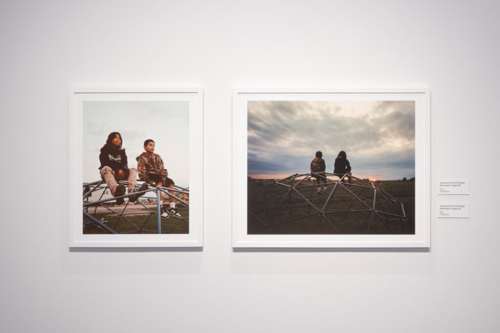 Two photos in white frames hang side by side on a gallery white wall.