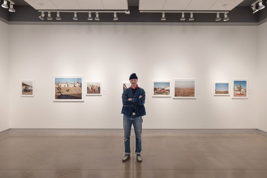 A man stands in front of his exhibition in the tomayko foundation gallery.