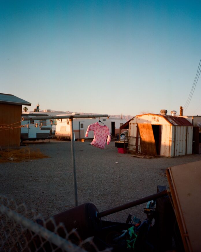 A landscape with clothes handing from clothes lines and sheds in the background.