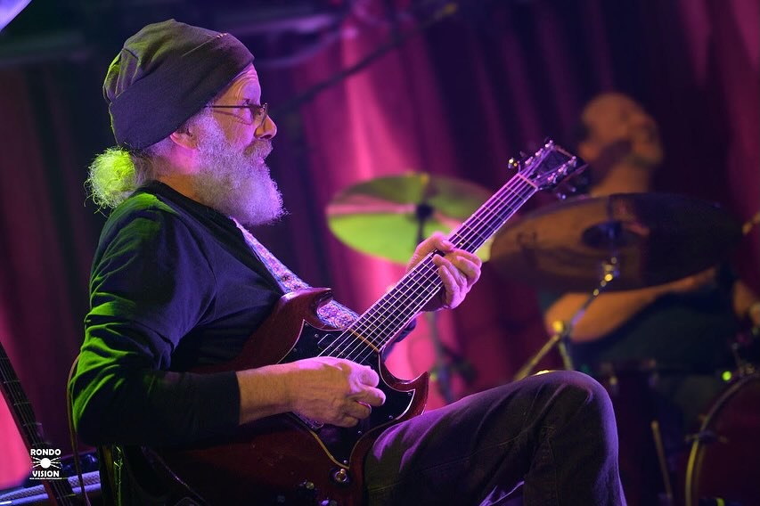 A man plays his guitar on stage.