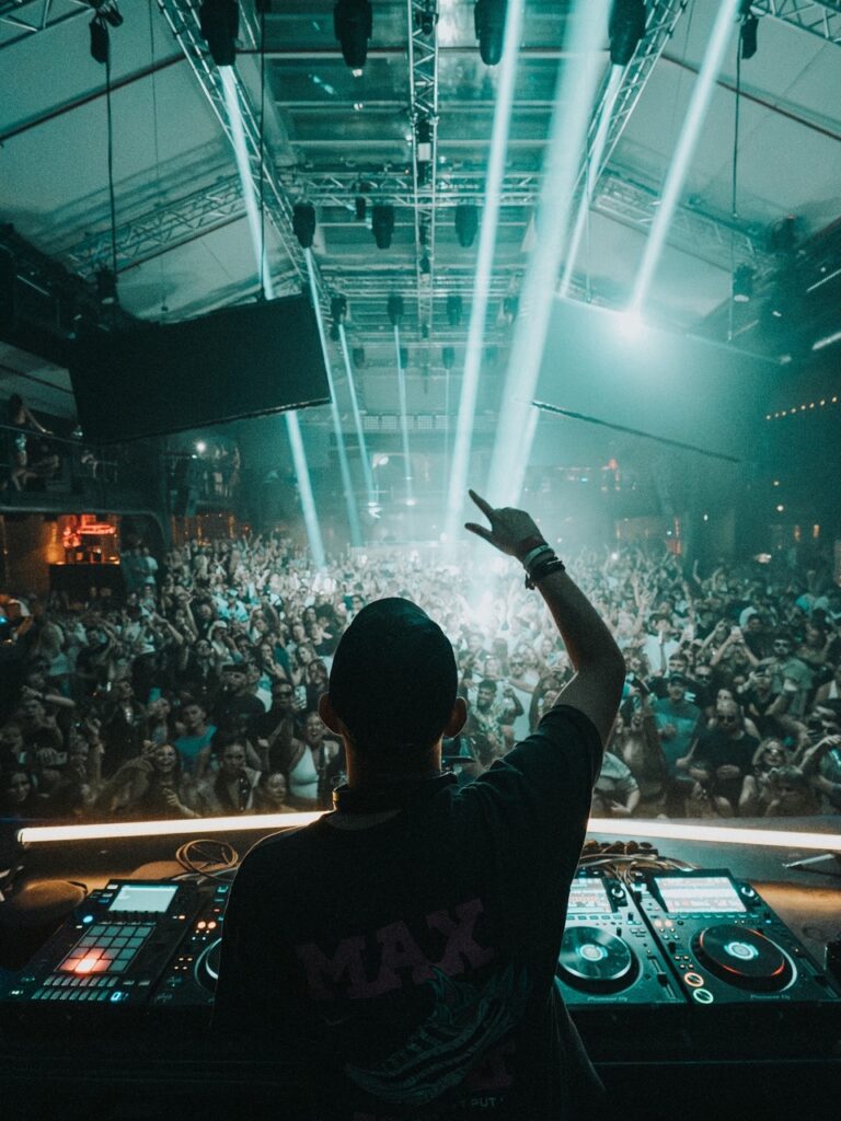 A DJ puts his hand up in the air as he plays for a large party.