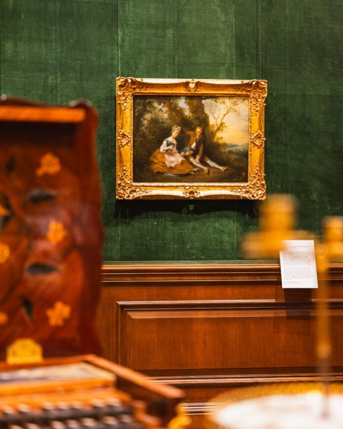 An art painting hangs on a green museum wall at The Frick Pittsburgh.