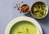 Asparagus Soup A green soup sits in a bowl with asparagus spear heads throughout the soup and in a bowl above the soup.