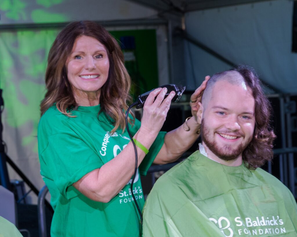 A woman shaves a man's head.