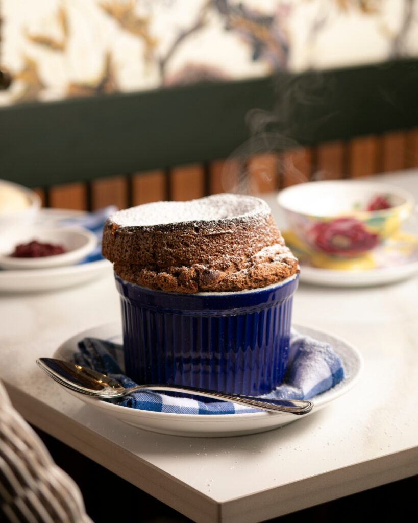 A towering chocolate soufflé dusted with powdered sugar and served in a blue ramekin at Poulet Bleu in Lawrenceville.