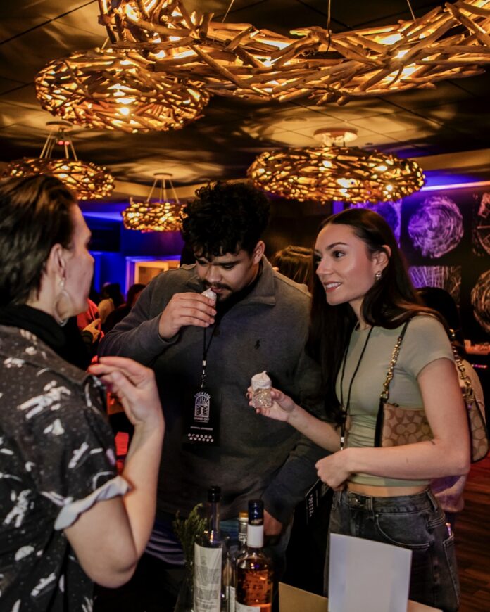 A bartender twos two people small cocktails with foam on top.