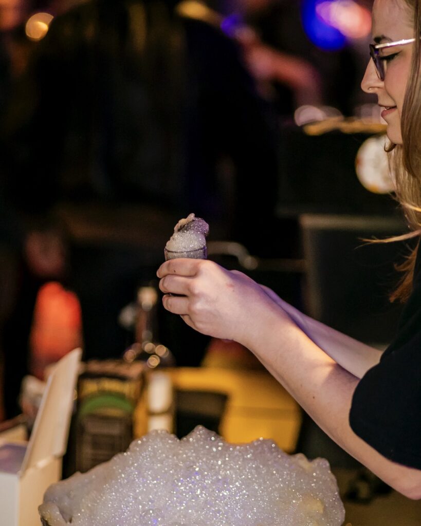 A woman scoops foam onto a small cocktail.