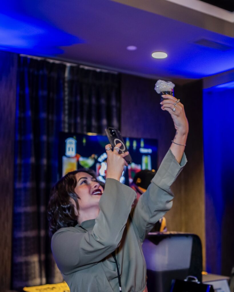 A woman takes a picture of a cocktail in the air.