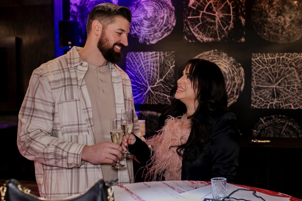 A man and woman cheers and look at each other.