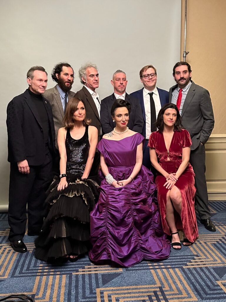 A group of women in dresses and men in suits and ties.