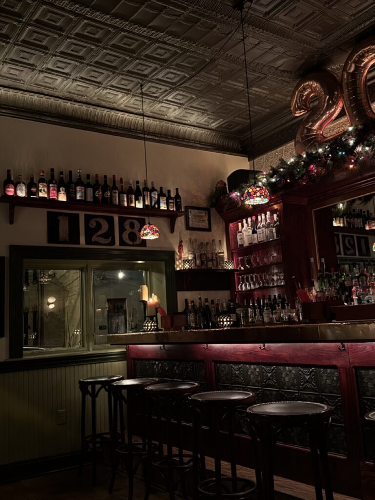 The inside of a low-lit bar with stool seats.