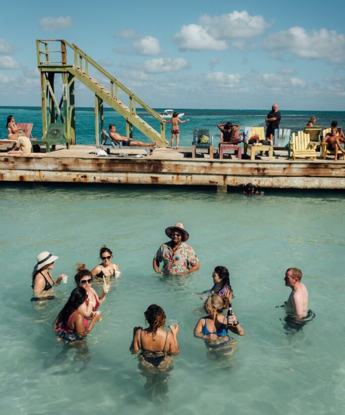A bunch of people wade in the water by a wood deck.