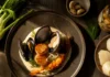 Devour Local: Recipes that Use Western Pennsylvania Jarred Ingredients Filipino White Adobo Seafood Bouillabaisse featuring sautéed scallops, prawns, clams, and mussels on a bed of white garlic rice puree, garnished with fresh dill and fennel.