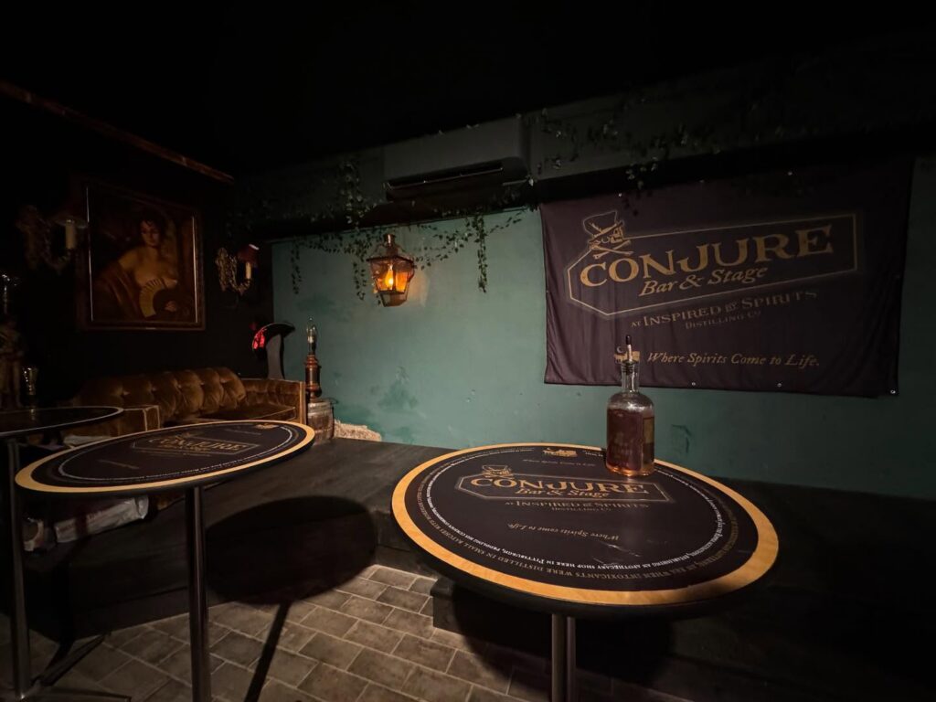 Darkly lit tables in front of the conjure stage at a bar.