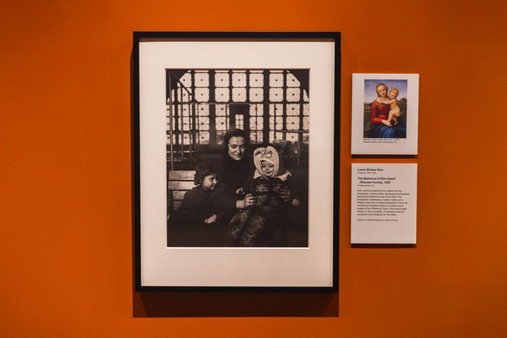 A framed photo of an immigrant family on an orange gallery wall.