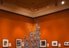 Seeing Ourselves in ‘Lewis Hine Pictures America’ An orange gallery wall covered in photos.