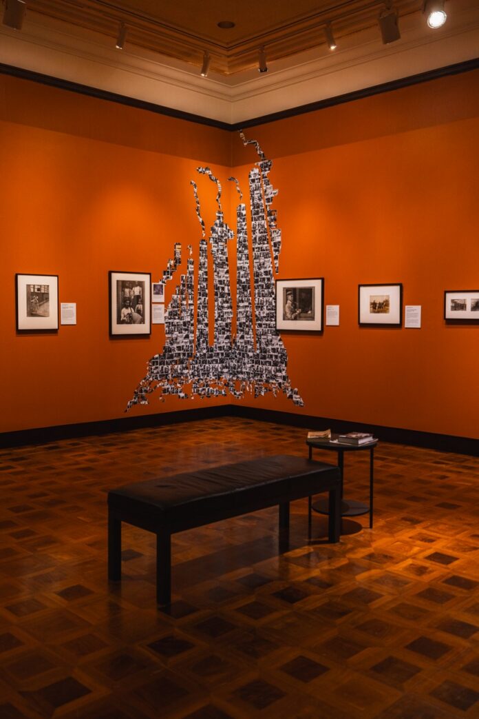 An orange gallery wall covered in photos.