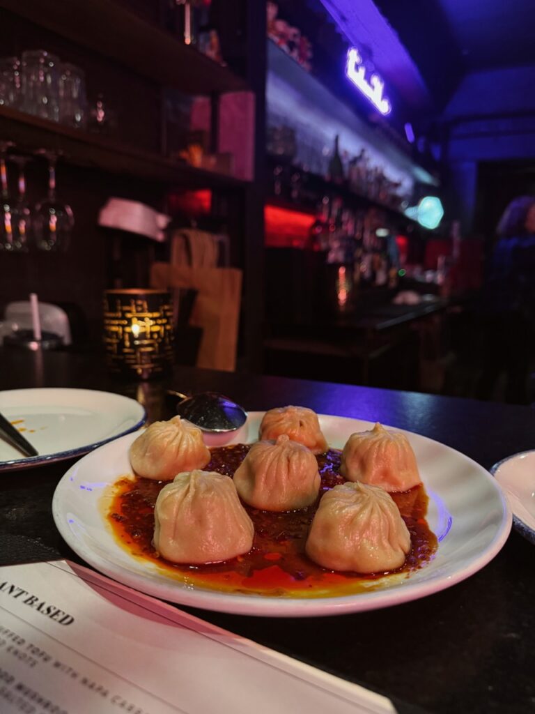 A white plate full of dumplings in a red sauce.
