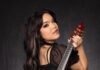 Violinist Mia Asano on Rocking the Classical Music World Mia Asano in a black dress with her red flying v violin over her shoulder.