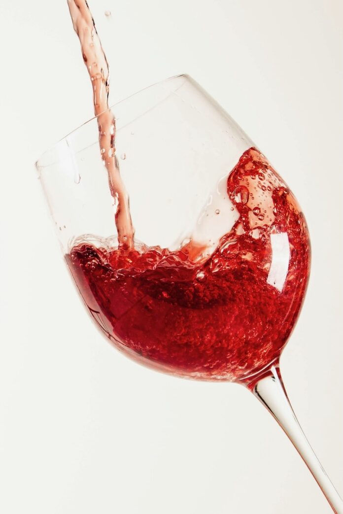 Must Try Wines 2026 TABLE Magazine Red wine pours into a wine glass against a wine background.