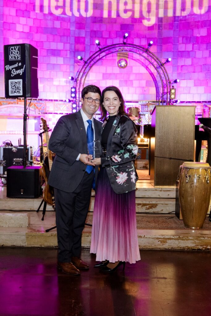A man in a suit and a woman in a pink and purple dress stand together.