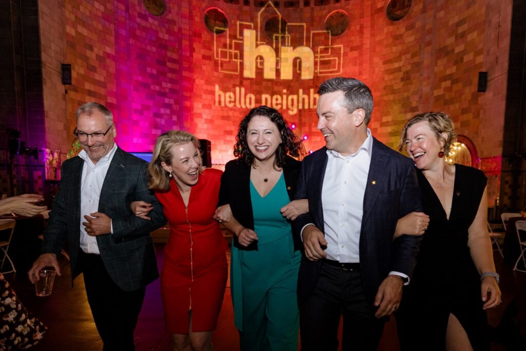 three women and two men connect arm in arm.