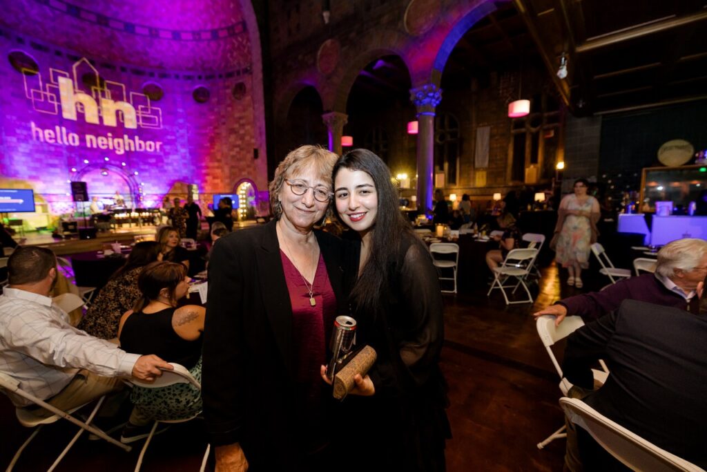 A woman in a red shirt and a younger woman in black stand together.