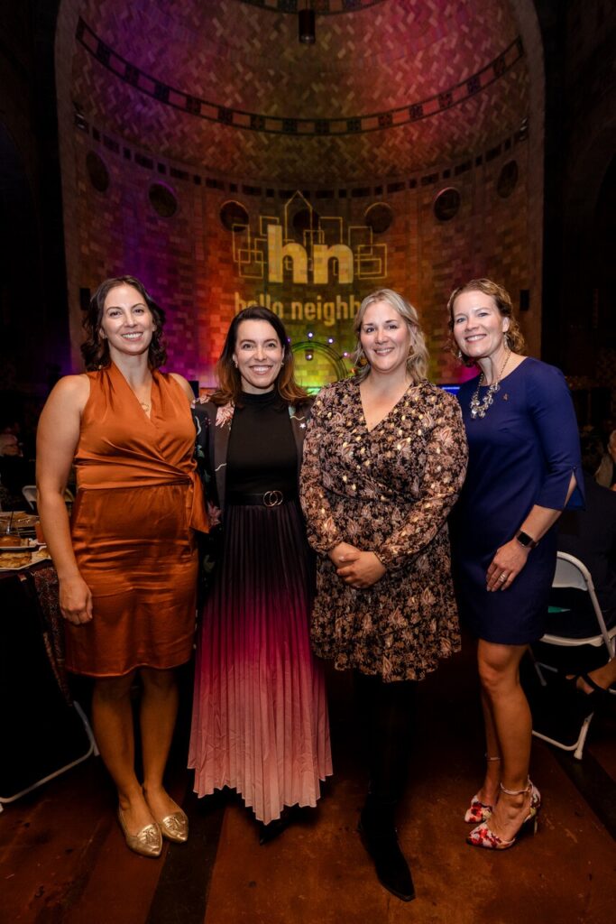 Four women stand together under red, orange, and purple lights.