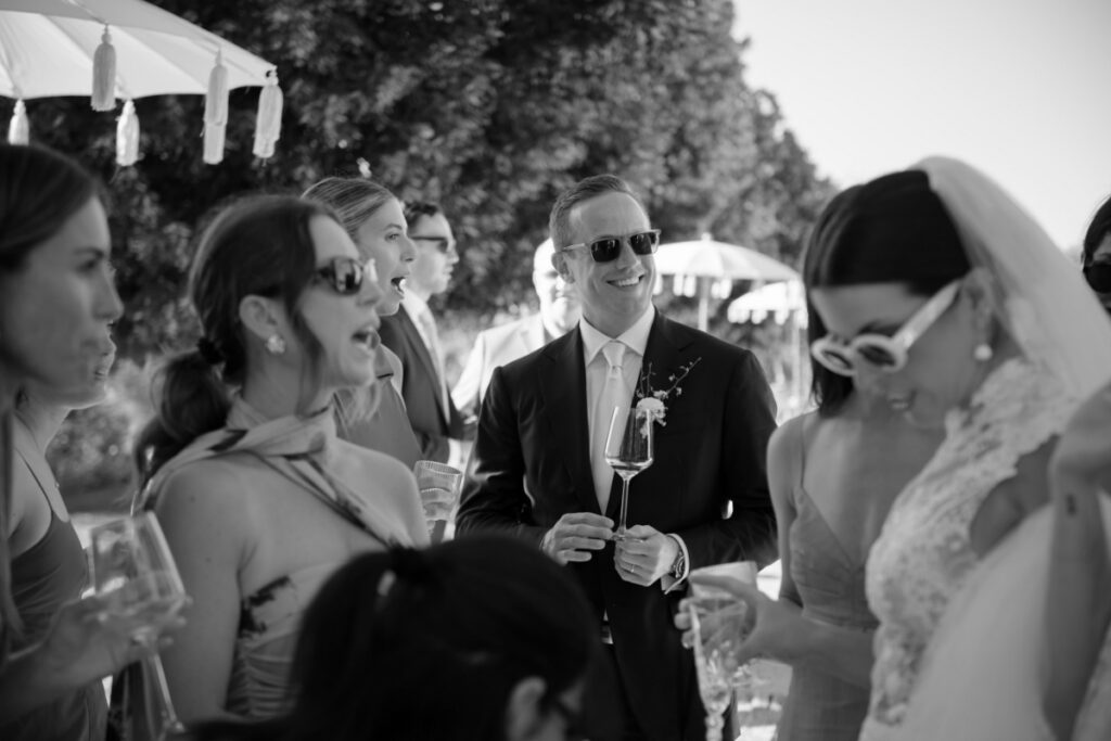 A black and white photo of groom Philip Caputo smiling and holding a wine glass.