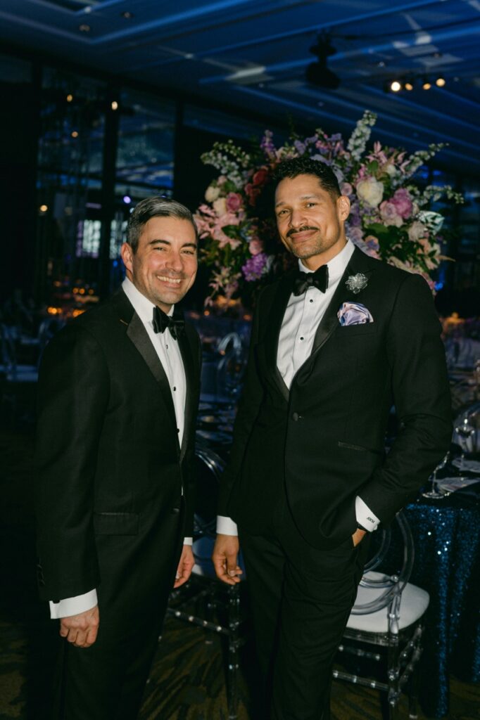Two men in tuxes stand together.