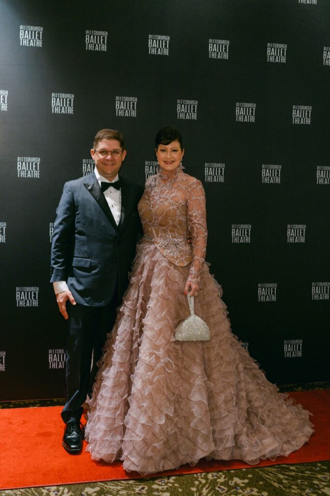 A man in a suit and bowtie stands with a woman in a long pink dress.