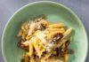 Penne with Asparagus and Lemon A light green bowl full of penne pasta with cheese and asparagus as a fork sits below the bowl.