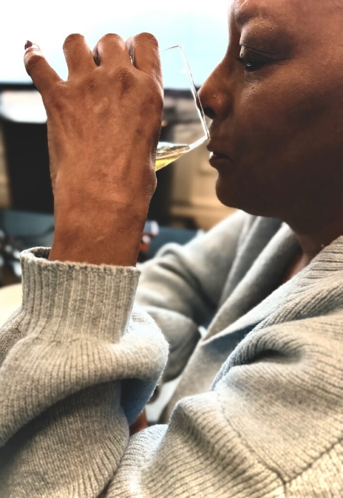 A woman drinks beer from a wine glass.