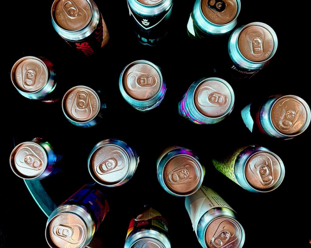 An array of beer cans sit on a table.