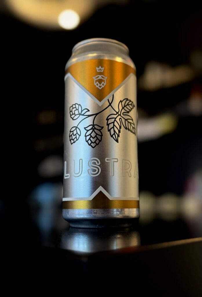 A silver and gold can of beer on a black counter.