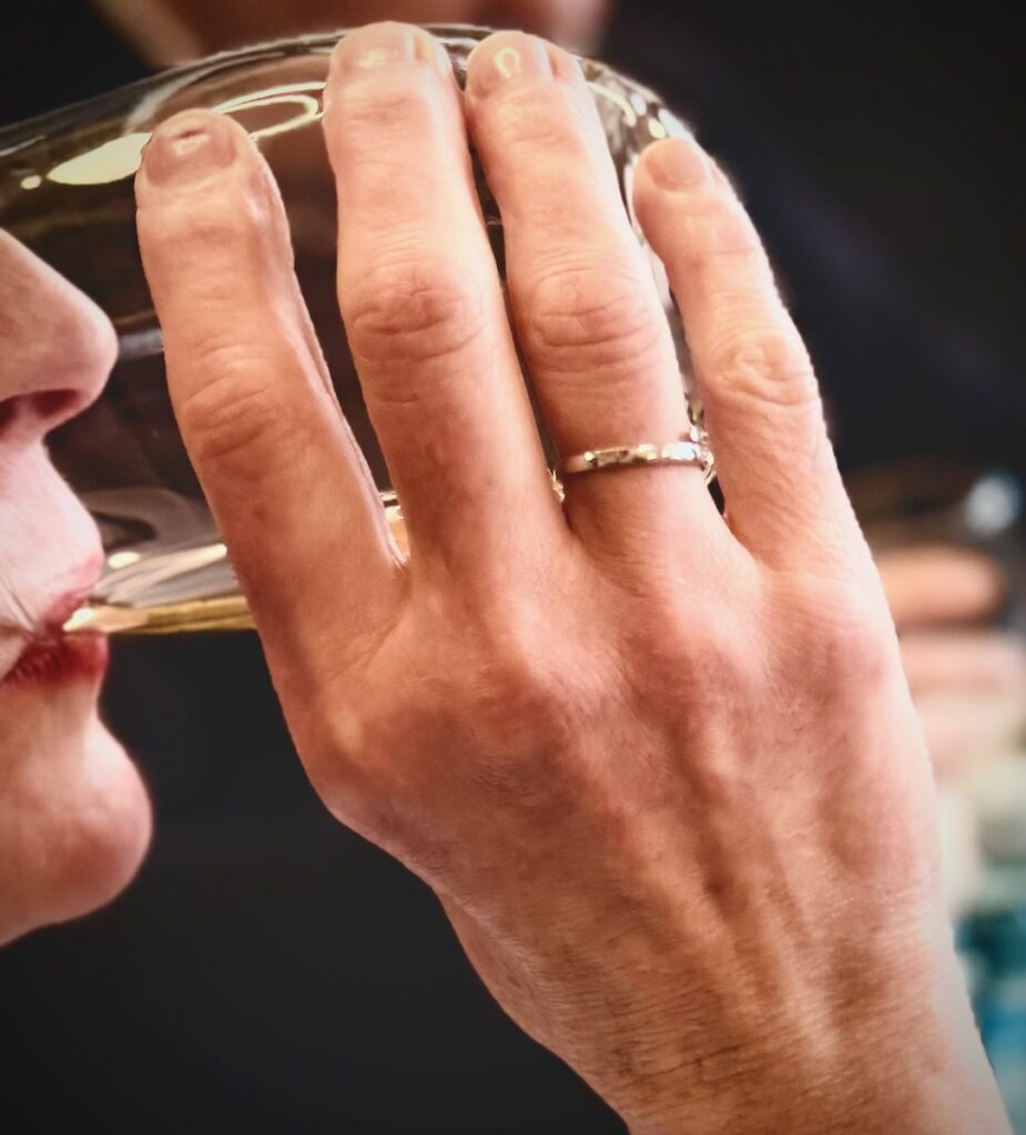 A woman sips beer from a glass.