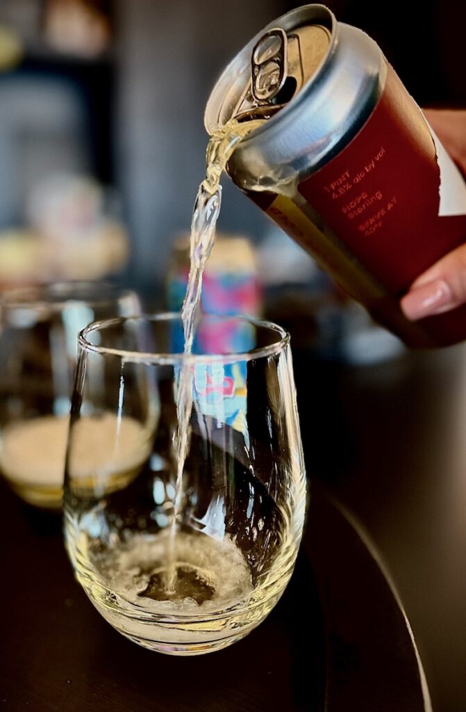 A person pours beer into a wine glass.