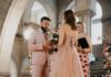 Pittsburgh Party Planners to Hire for Weddings, Birthdays, and More A man and woman hold hands at a wedding alter with flowers and candles surrounding them on the stairs.