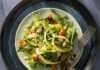 Shaved Asparagus Salad A plate full of shaved asparagus and croutons with a salad dressing container in the bottom left corner.