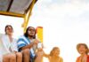 The Best Spring Break Party Destinations for Beaches and Booze A couple sits on a lifeguard stand as another couple stands beside it on the beach.