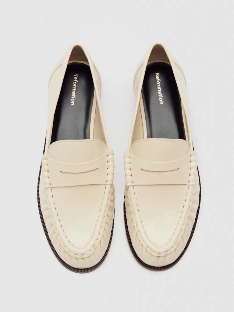 Cream colored loafers on a white background.