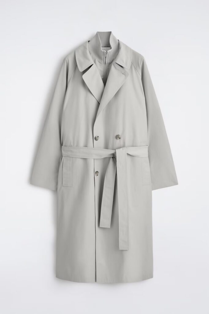 A pale grey trench coat with the belt tied.