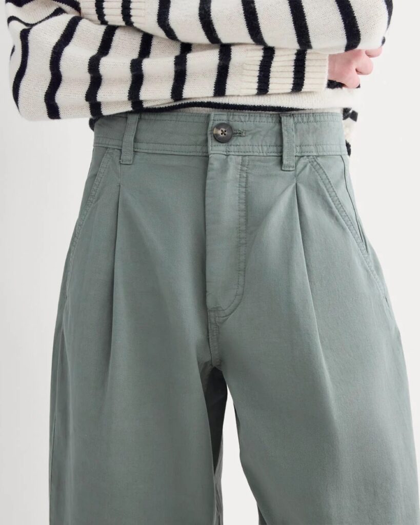 A woman wearing a striped shirt and blue trousers.