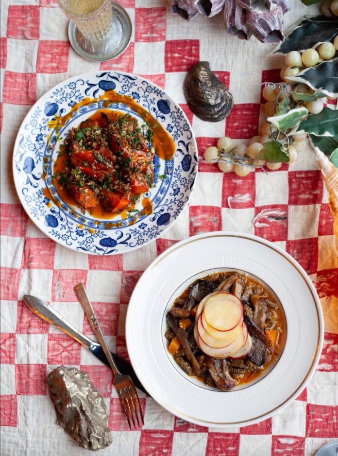 A red and white plaid tablecloth with two plates, one blue pattern and one white holding food inside.